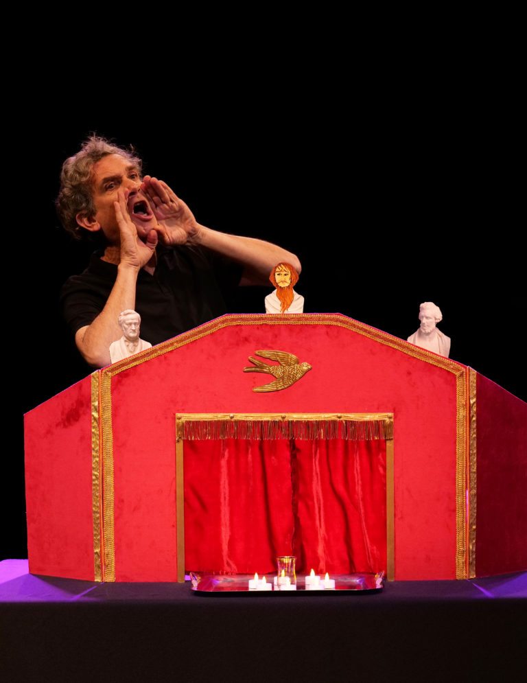 Derrière un castelet rouge, un comédien conte avec énergie l'univers de Wagner. Une image qui évoque un théâtre de récit, musical et plein d'humour.